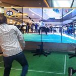 Hombre interactuando con video wall mediante juego de realidad aumentada